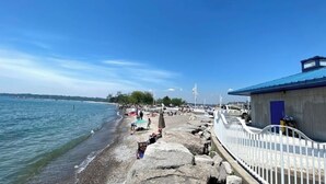 A coastal area with a rocky shoreline, a pier, and a building with a blue roof. - Furnished Family Home ★ KING BED ★ Parking ★ BBQ ★ Backyard ★ Discounted Price (Pickering)