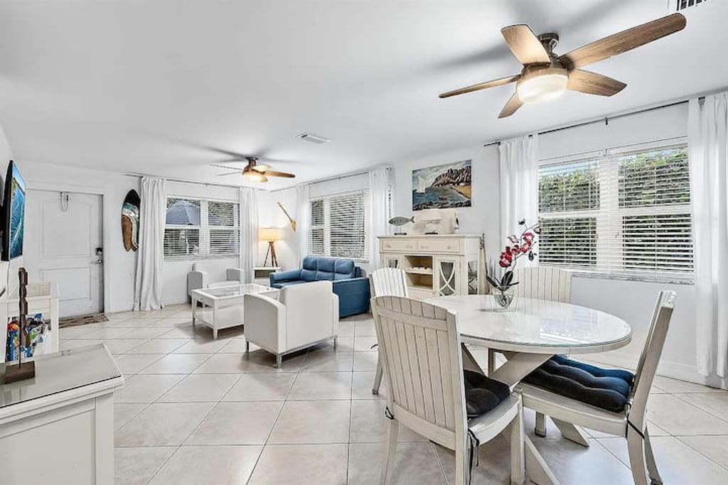 A spacious living area with a dining table, two sofas, and ceiling fans.