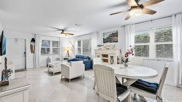 A spacious living area with a dining table, two sofas, and ceiling fans.