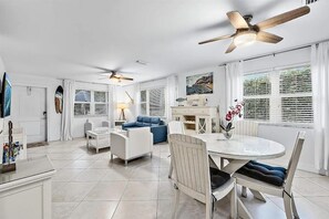 A spacious living area with a dining table, two sofas, and ceiling fans.