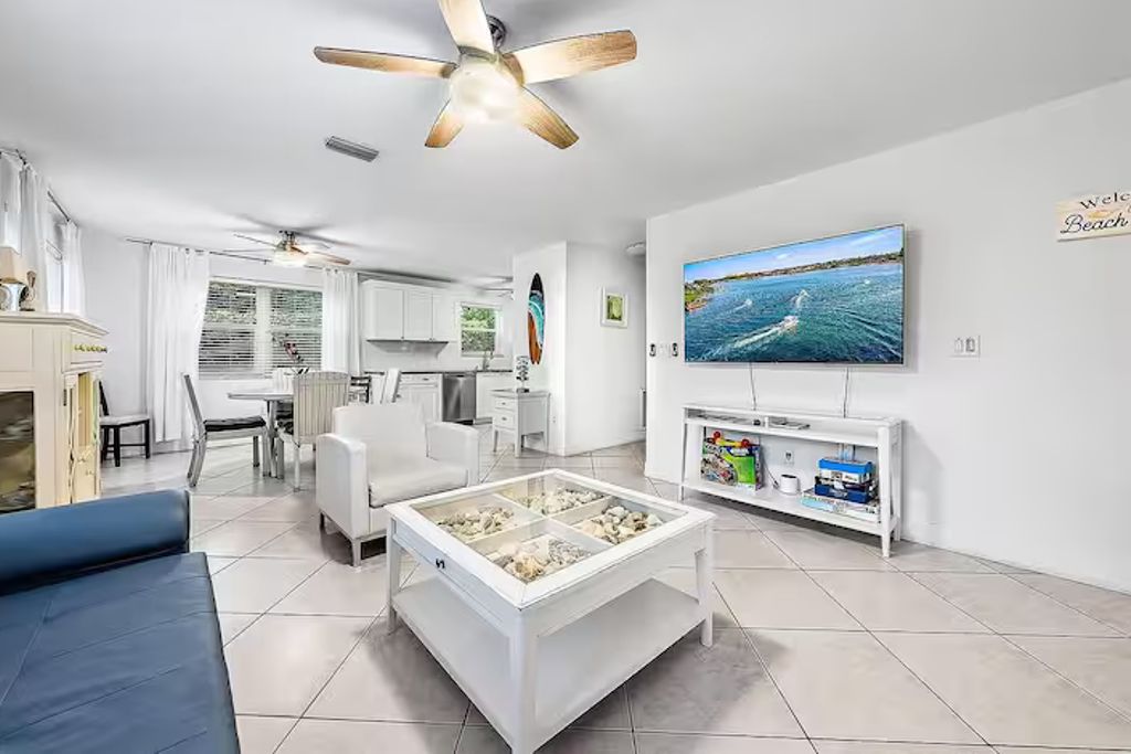 Un salon moderne avec un téléviseur, une table basse en verre et un ventilateur de plafond.