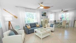 A spacious living room with a sofa, armchairs, a coffee table, and a dining area with chairs and a table.