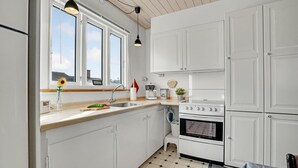 A modern kitchen with white cabinets, a large window, and a built-in oven. - 3 bedroom amazing home in Give (Give)