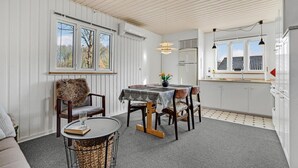 A dining area with a round table, chairs, and a small side table with a book and glass. - 3 bedroom amazing home in Give (Give)