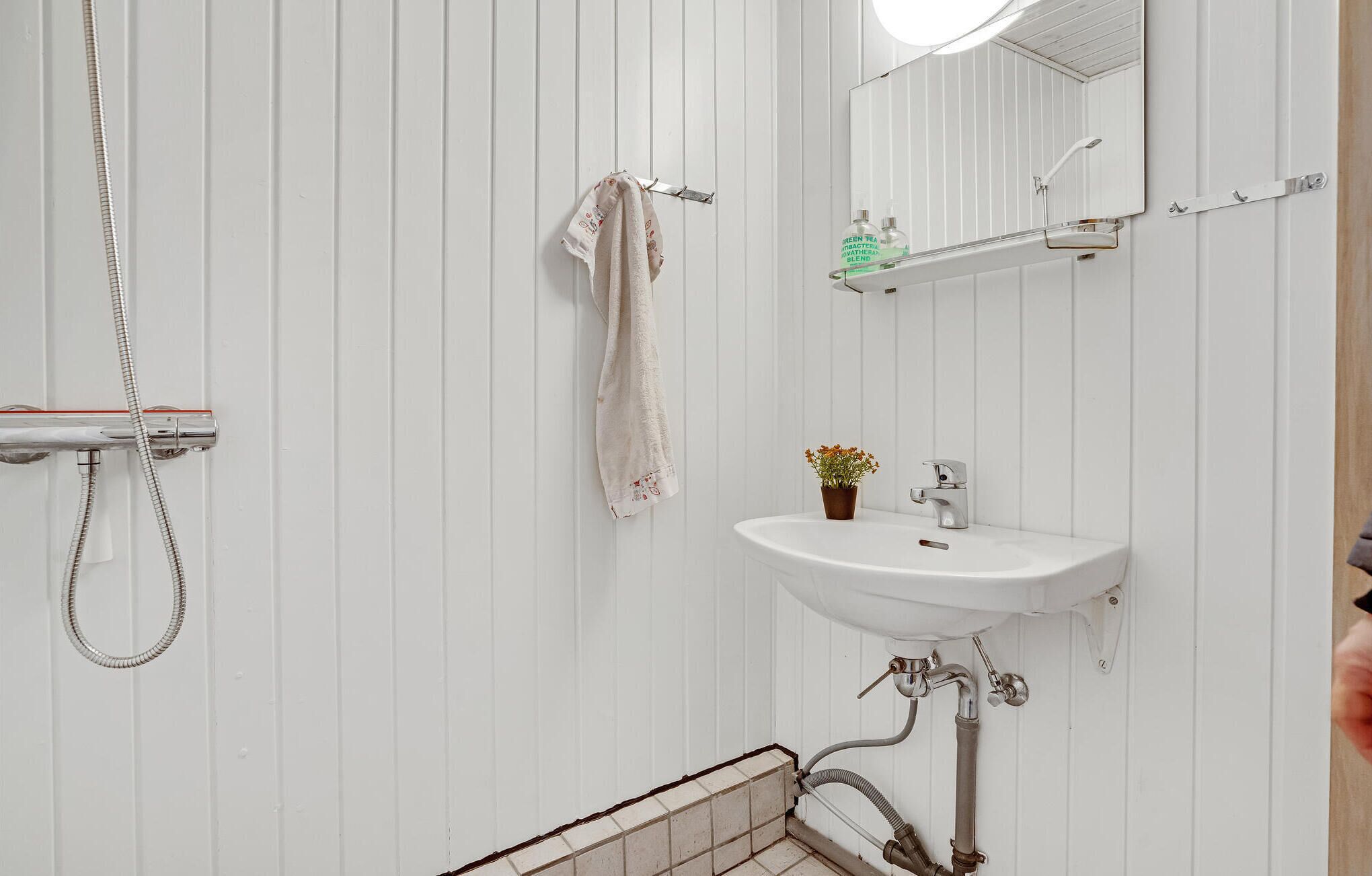 A bathroom with a white sink, a mirror, a towel rack, and a shower.