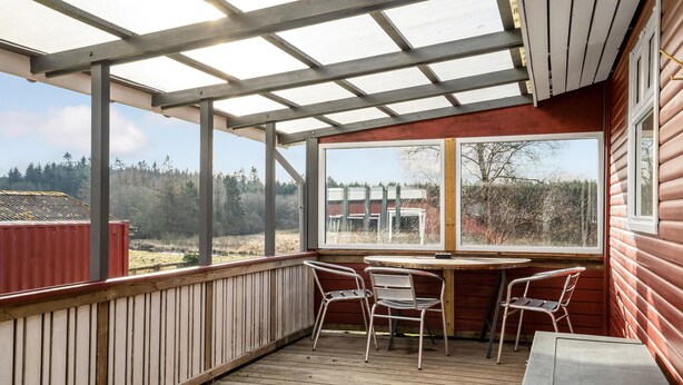 A covered outdoor area with a wooden deck, metal chairs, and a table. - 3 bedroom amazing home in Give (Give)