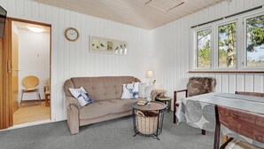 A cozy room with a beige sofa, a round coffee table, a dining table with chairs, a clock on the wall, and a window with a view of trees. - 3 bedroom amazing home in Give (Give)
