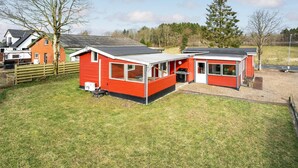 A red mobile home with a small attached garage, a patio area, and a lawn. - 3 bedroom amazing home in Give (Give)