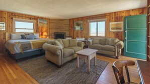 A cozy room with a bed, two sofas, a small table, and a fireplace.