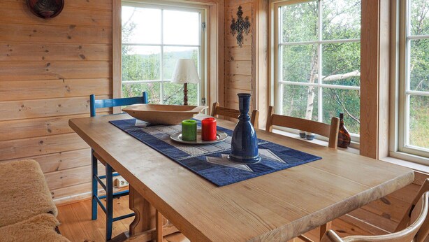 A wooden dining table with a blue placemat, two candles, and a vase. - Awesome home in Ustaoset with WiFi (Ustaoset)