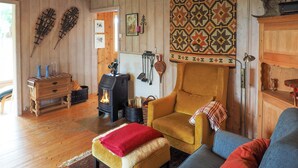 A cozy living room with a wooden interior, a stone fireplace, a sofa, and a chair. - Awesome home in Ustaoset with WiFi (Ustaoset)