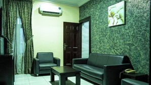 A living room with a sofa, two armchairs, a coffee table, a telephone, and an air conditioning unit. - Where Elegance, Comfort, and Prestige Meet. (Delta)