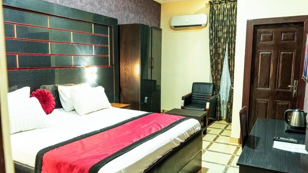 A hotel room with a large bed, a desk, a wardrobe, and a door. - Where Elegance, Comfort, and Prestige Meet. (Delta)
