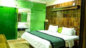 A hotel room with a bed, a wooden headboard, a green wall, and a wooden bench. - Where Elegance, Comfort, and Prestige Meet. (Delta)