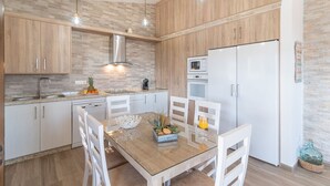 A modern kitchen with wooden cabinets, a stainless steel range hood, a microwave, and a white refrigerator.