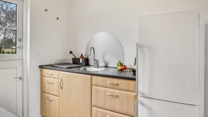 A compact kitchen with a sink, a refrigerator, and wooden cabinets. - 2 bedroom stunning home in Rødby (Rødby)