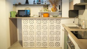 A compact kitchen with a microwave, kettle, and a decorative shelf with small items. - Bay view house in the heart of the Abbaye district (Saint-Valery-sur-Somme)