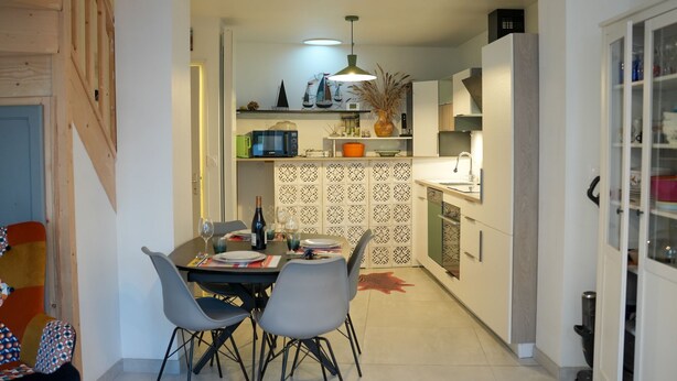 A modern kitchen with a dining area, featuring a central island, pendant lighting, and a decorative backsplash. - Bay view house in the heart of the Abbaye district (Saint-Valery-sur-Somme)