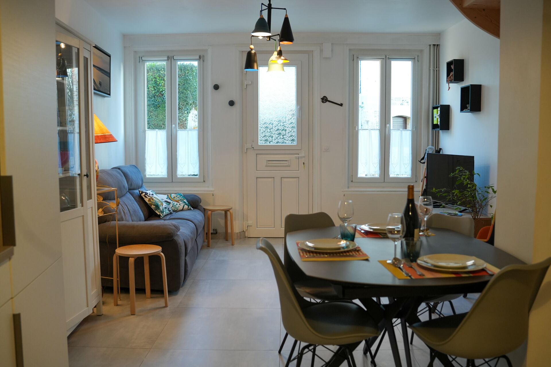 A cozy living room with a sofa, a dining table set for two, and a kitchen area visible through an open door.