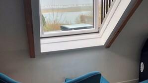 A room with a skylight, two teal chairs, and a wooden floor. - Bay view house in the heart of the Abbaye district (Saint-Valery-sur-Somme)