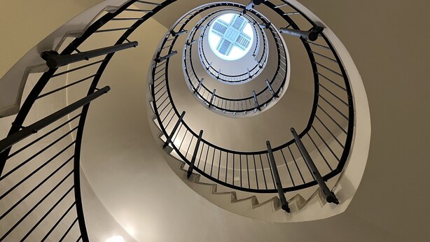 Un escalier en colimaçon surmonté d’une lucarne centrale.