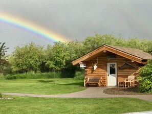 En træhytte med et skilt, der viser, at den er åben, en bænk udenfor og en dekoration med et hjortedekoreret kranie.