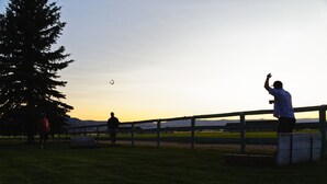 A person standing on a wooden fence in a grassy field with a sunset in the background. - Studio Style Cabin - In the heart of all things outdoors (Dillon)