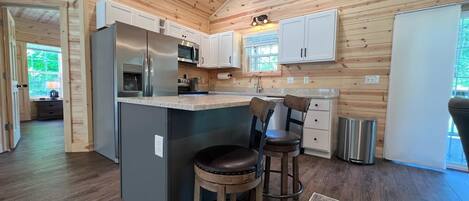 A modern kitchen with wooden paneling, stainless steel appliances, and a bar area with stools.