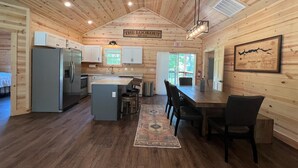 A cabin interior with a kitchen, dining area, and an exit sign.