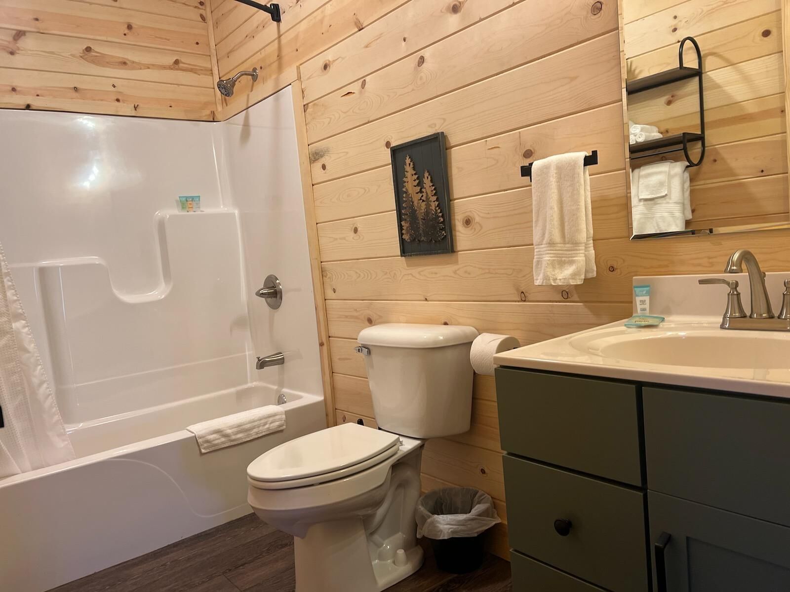 Un baño con bañera, inodoro, lavamanos y paredes de madera.