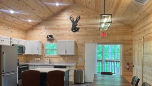 A wooden cabin-style kitchen with white cabinets, a dining table, and chairs.