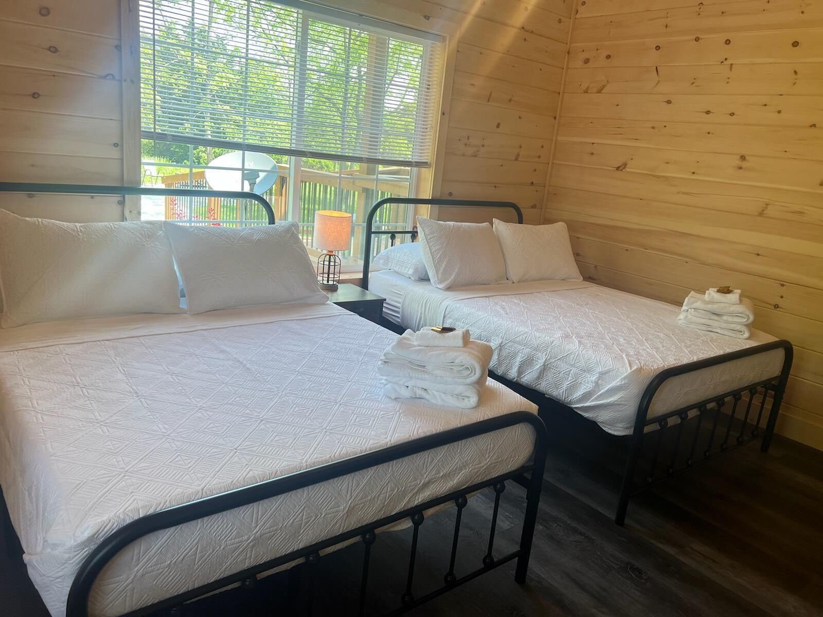 Een kamer met twee bedden, elk voorzien van witte beddengoed en kussens, en een klein tafeltje met handdoeken.