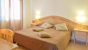Une chambre à coucher bien rangée, avec un lit en bois, deux tables de chevet avec des lampes, une chaise en bois et une petite table.