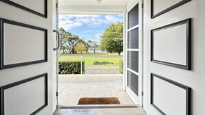 Una entrada que da a un espacio exterior cubierto con vista a un parque y un lago.