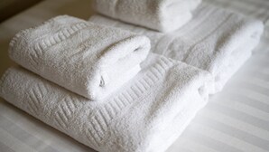Sauber gefaltete weiße Handtücher auf einem gestreiften Bett.
