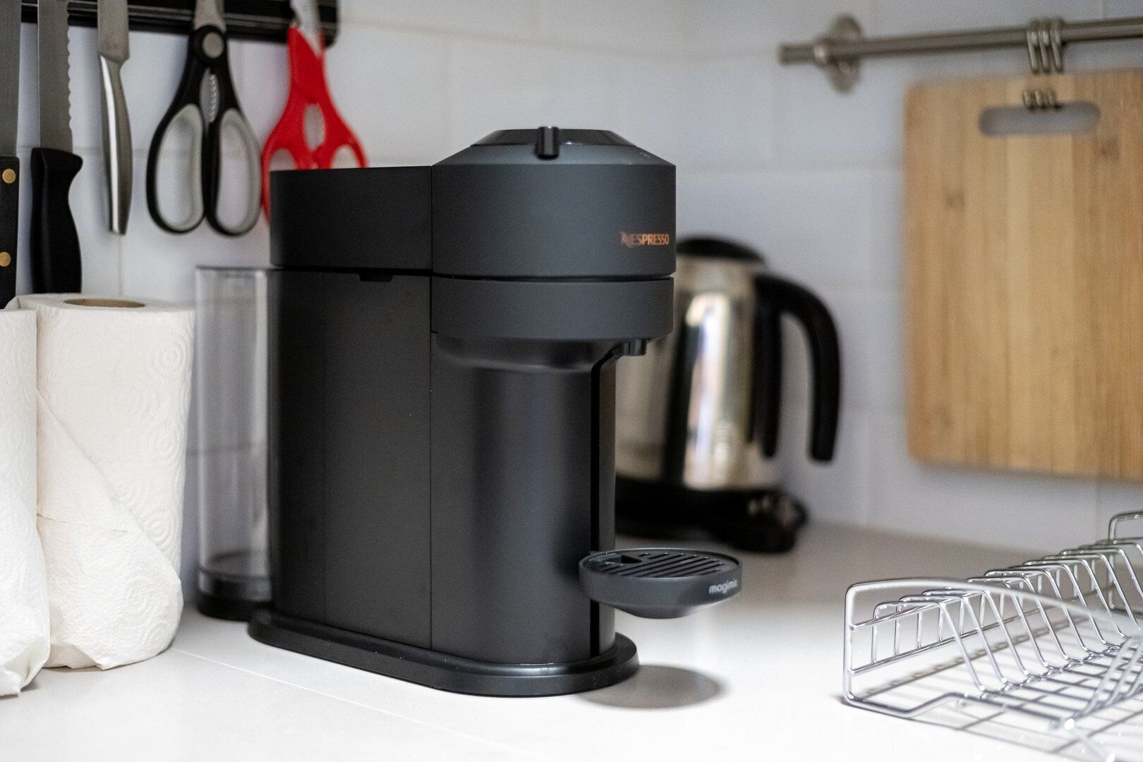 Een keuken met een zwarte koffiezetapparaat, een waterkoker en een afwasschaal.