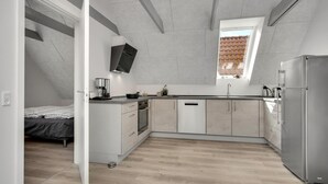 Eine kompakte Küche mit Backofen, Kühlschrank und einem Fenster über der Spüle.