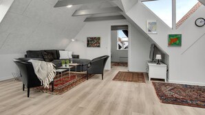 Ein Loft-Wohnzimmer mit hohen Decken, einer Couch, einem Couchtisch und einer TV-Konsole.
