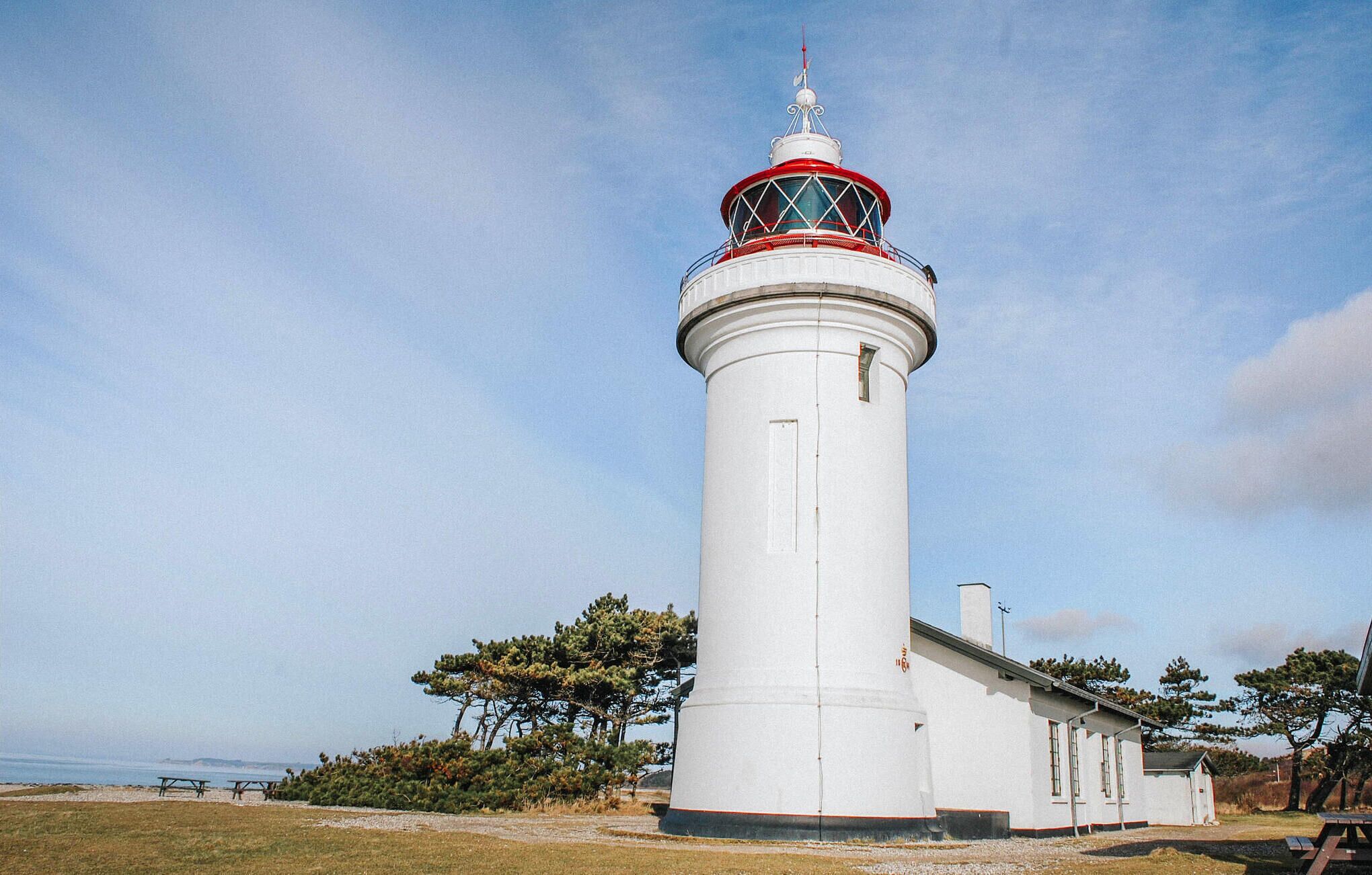 A lighthouse with a white cylindrical tower and a red and white lantern room.