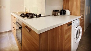 Eine moderne Küche mit Holzschränken, einem Gasherd, einem Backofen, einer Spüle und einer Waschmaschine.