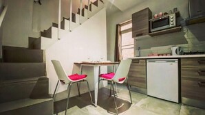 A compact kitchen with a dining area, a microwave, and a refrigerator. - Malta Suites 4 terrace (Isla)