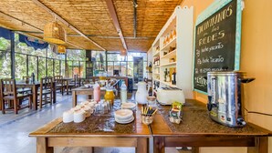 Ein Restaurant mit rustikalem Ambiente, mit Holztischen und -stühlen, einer Kreidetafel als Speisekarte und einer Kaffeestation.