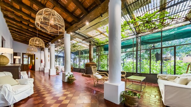 Eine geräumige Lobby mit Schachbrettfußboden, weißen Sofas und hängenden Korblampen.