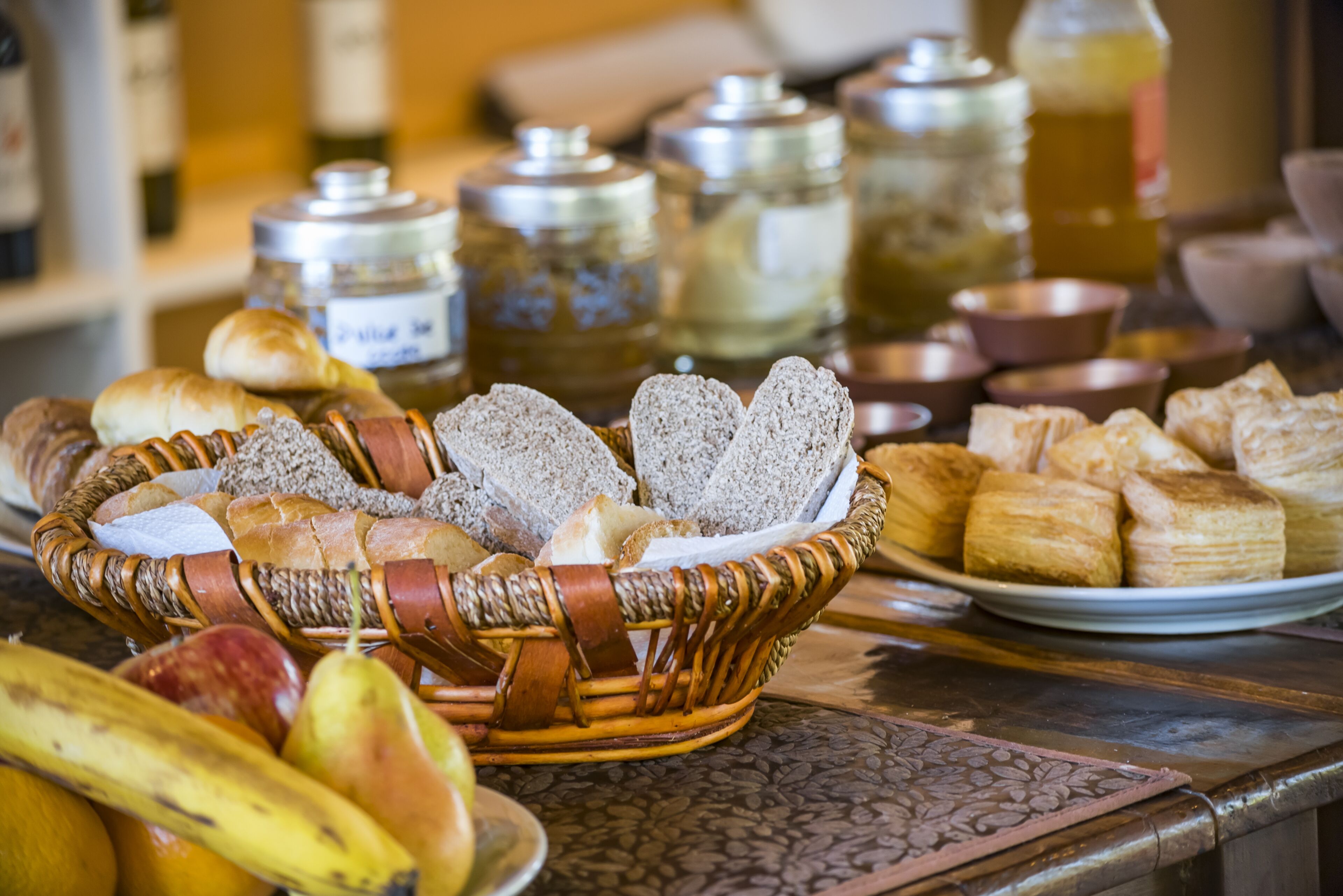Une table garnie de différents types de pain, de viennoiseries et de fruits.
