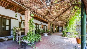 Ein überdachter Außenbereich mit Backsteinböden, Pflanzkübeln und einer Pergola.