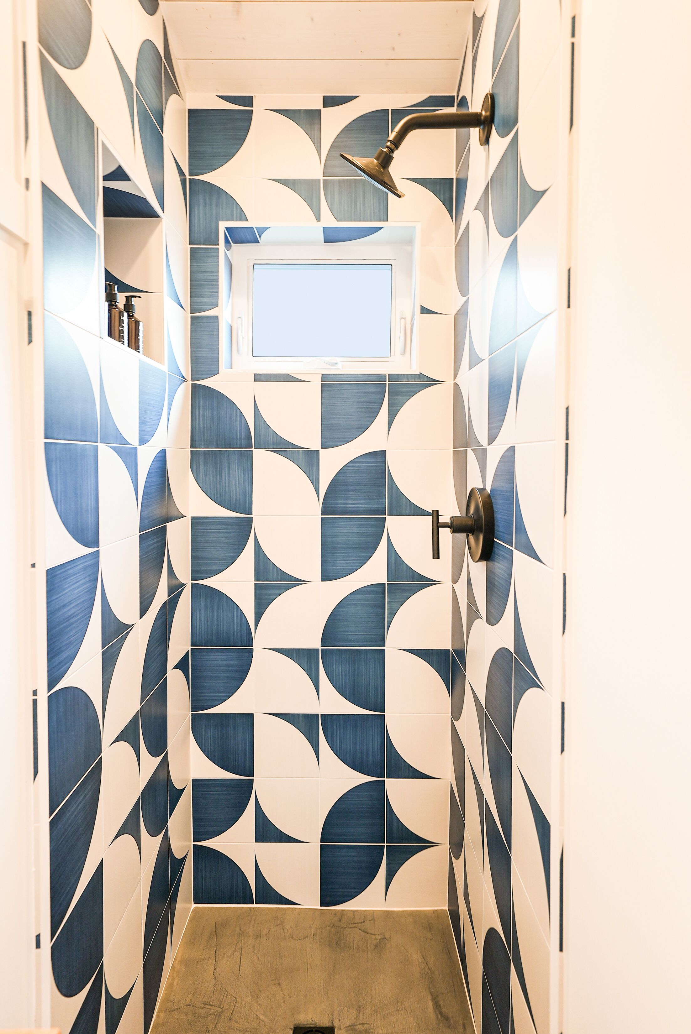 A bathroom with a geometric tile pattern, a showerhead, and a sink.