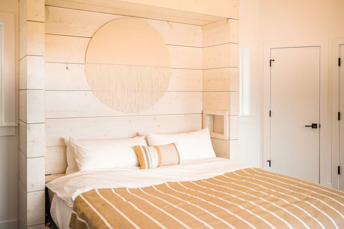 Une chambre à coucher avec une tête de lit en bois, une décoration murale ronde et un lit avec une literie à rayures.