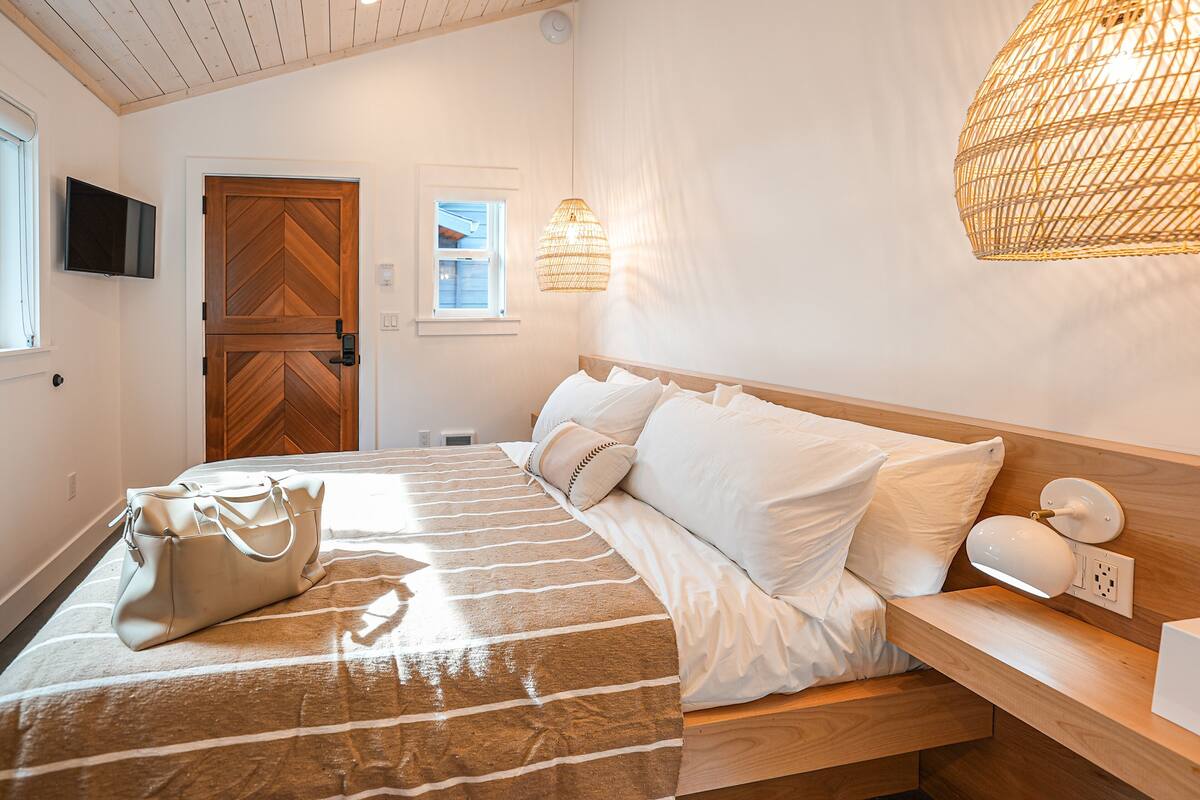 Une chambre à coucher avec un lit, une table de chevet, une lampe et un sac à main posé sur le lit.