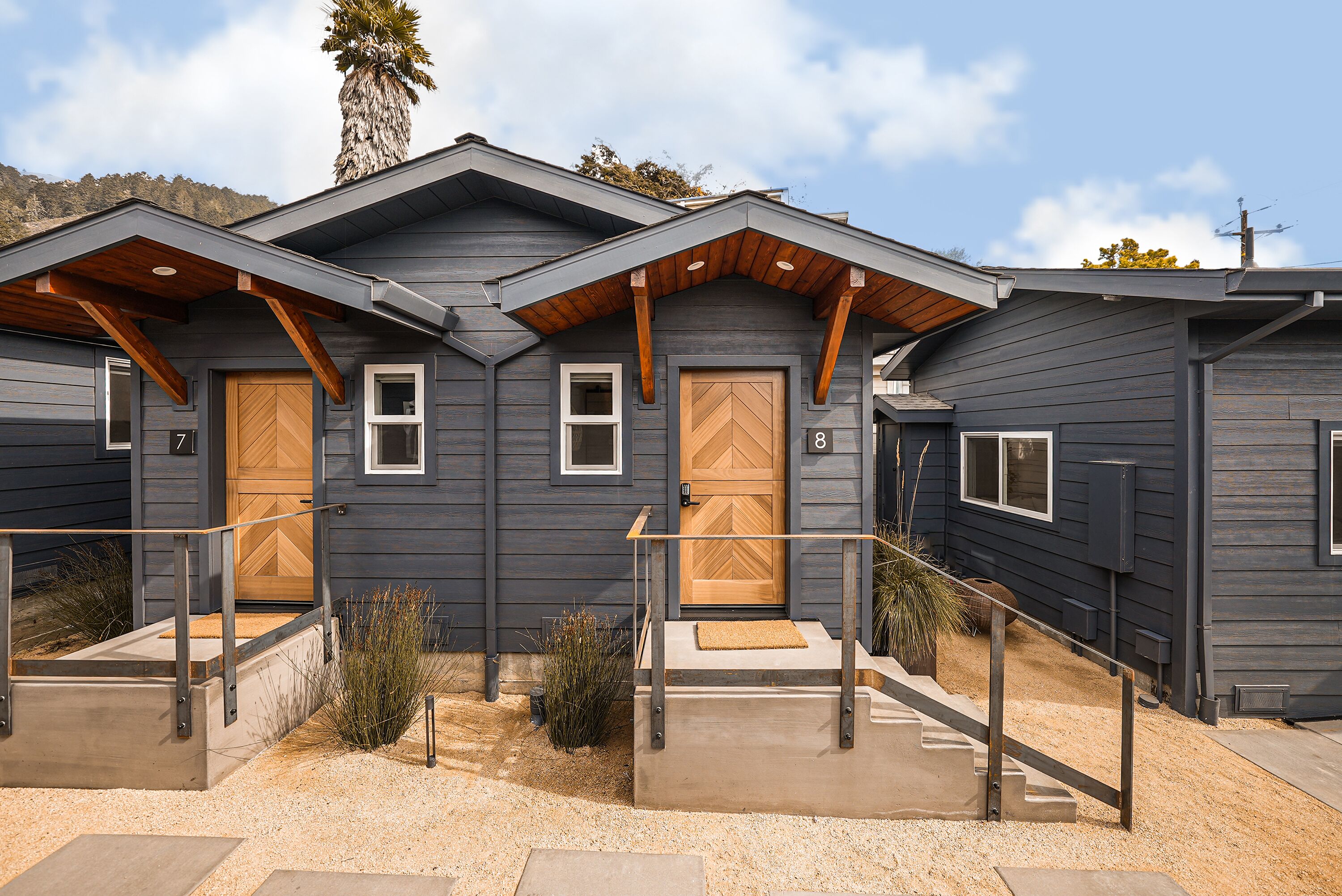 A modern two-story building with a dark exterior, wooden door frames, and a small porch area.