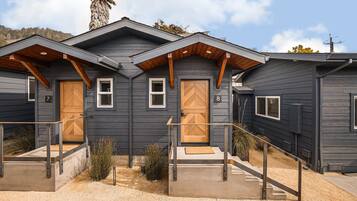 A modern two-story building with a dark exterior, wooden door frames, and a small porch area.